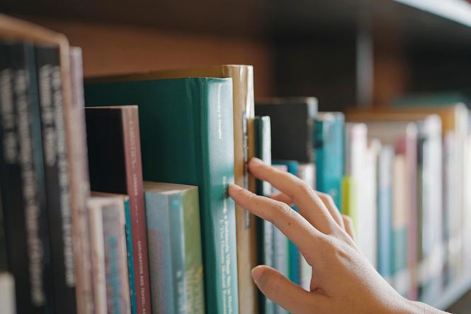 Hand greift in Bücherregal