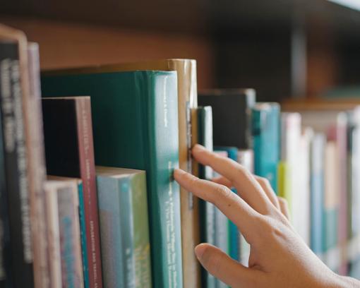 Hand greift in Bücherregal