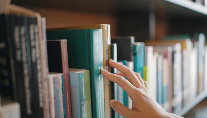 Hand greift in Bücherregal